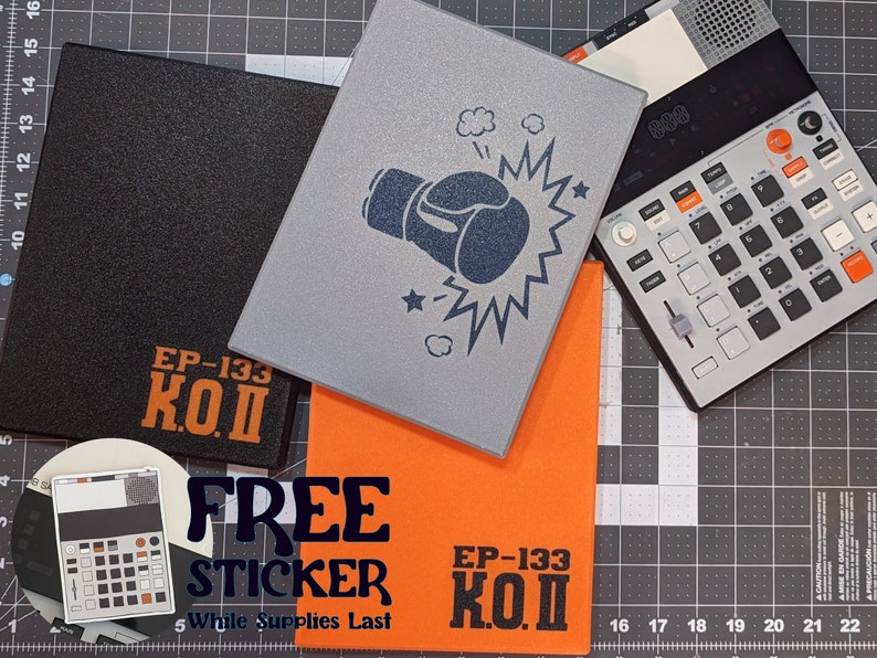 May include: A collection of electronic music production accessories. Includes a black case with "EP-133 K.O.II" text, a gray case with a boxing glove graphic, and an orange case with the same text. A gray music production device is also visible.
