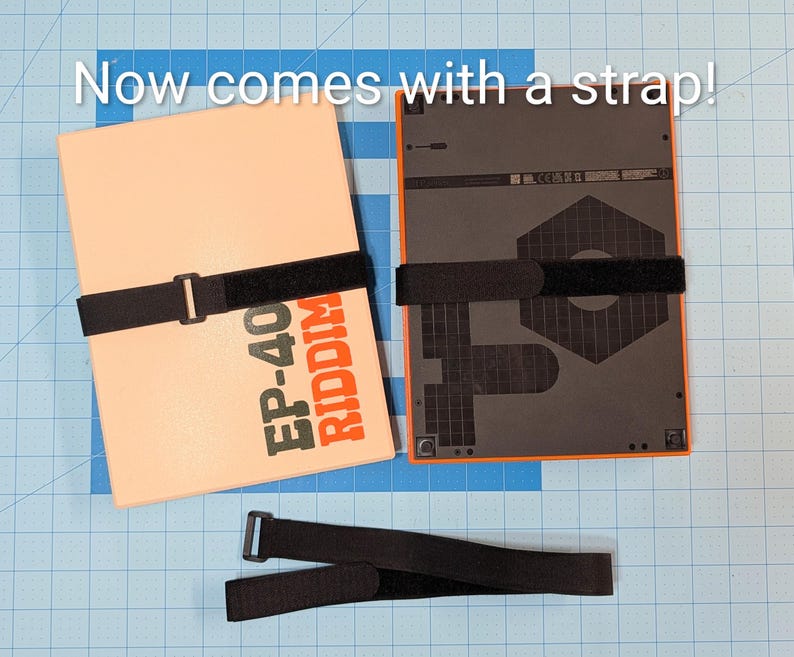 May include: Two rectangular electronic devices with black straps, one cream-colored with orange text reading "EP-40 RIDDIM", the other black with an orange border. A separate black strap is also visible. Text at the top reads "Now comes with a strap!"