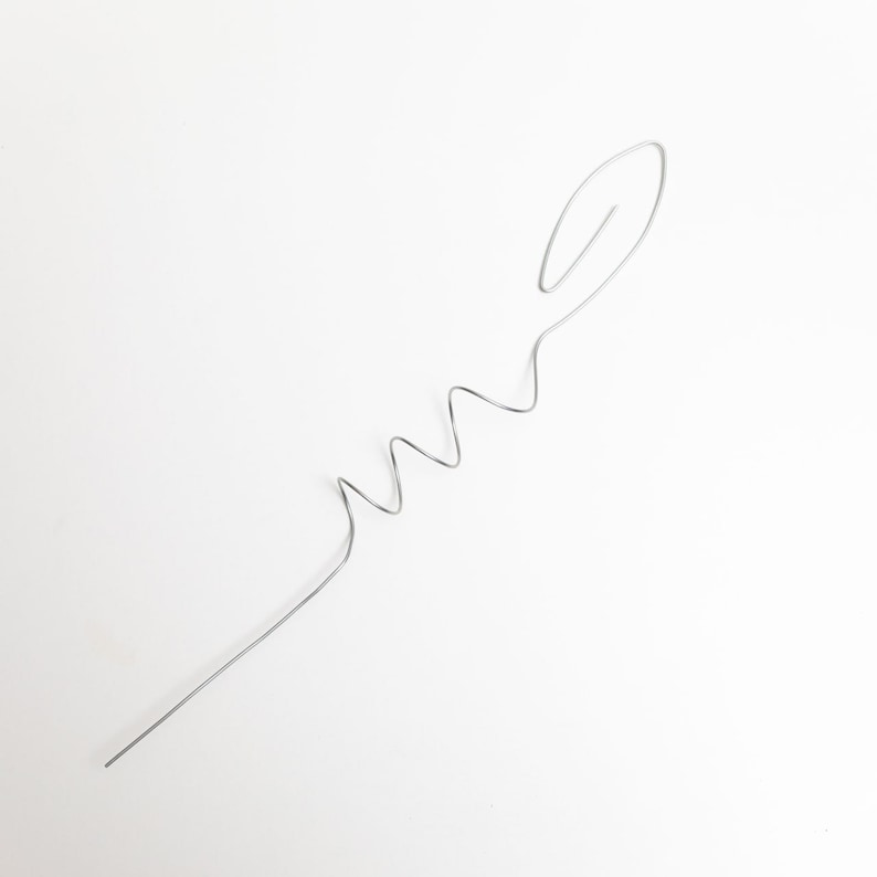 May include: A silver wire bent into a wavy shape with a loop at the end.