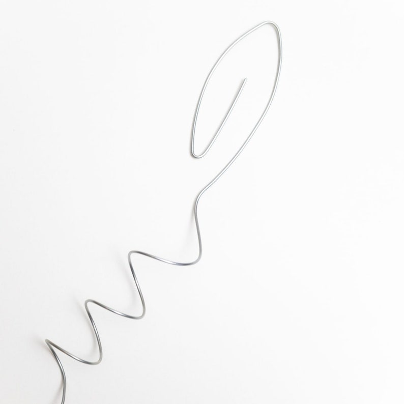 May include: A silver wire bent into a wavy shape with a loop at the top.