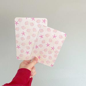 May include: A white ceramic mug with a black handle and the text "But First, Coffee" in a black, bold font. The mug is sitting on a wooden surface. The mug is approximately 4 inches tall.