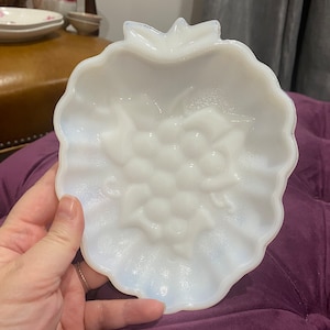 May include: White milk glass dish shaped like a grape cluster. The dish has a raised design of grapes and leaves.