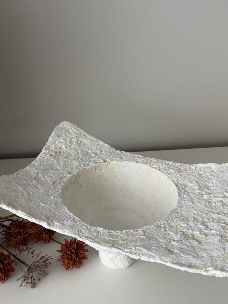 May include: A set of three ceramic mugs with a speckled, matte finish. The mugs are in shades of cream, light brown, and dark brown. Each mug has a simple, minimalist design and a rounded handle.