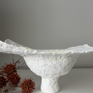 May include: A set of three ceramic mugs with a speckled, matte finish. The mugs are in shades of cream, light gray, and dark gray. Each mug has a simple, minimalist design and a rounded handle.