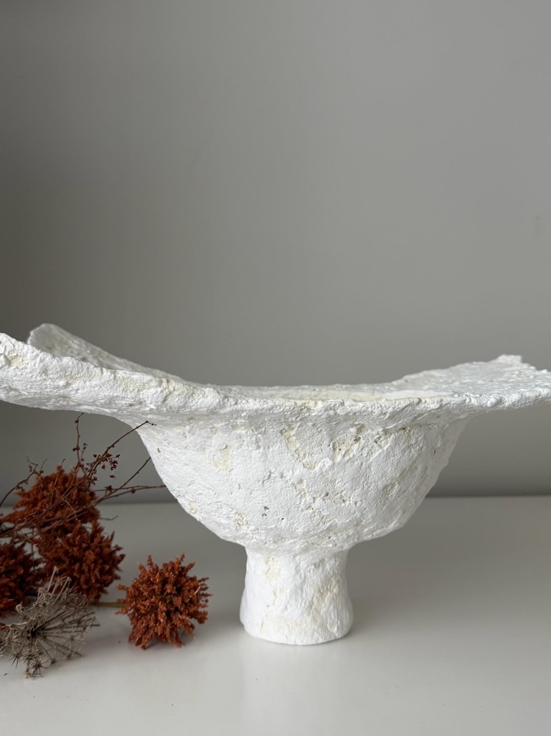 May include: A set of three ceramic mugs with a speckled, matte finish. The mugs are in shades of cream, light gray, and dark gray. Each mug has a simple, minimalist design and a rounded handle.