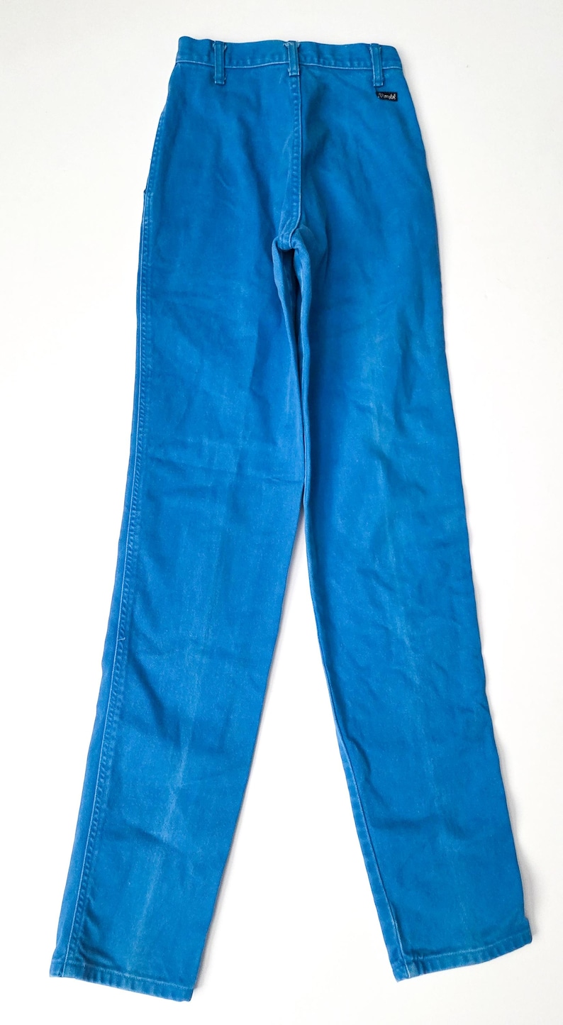 May include: Bright blue denim pants. The pants have a classic five-pocket design with a button and zipper closure. The pants are made of a sturdy denim material and have a straight leg cut. The pants are a vibrant shade of blue.