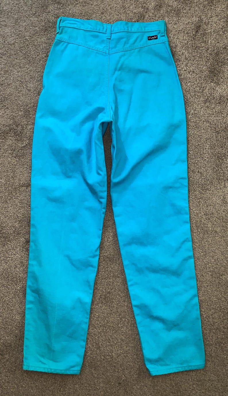 May include: A pair of turquoise blue trousers with a Wrangler label on the back right pocket.