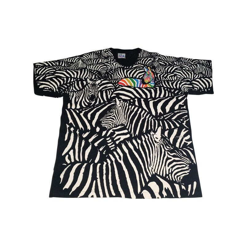 May include: Black t-shirt with a zebra print design. The shirt features a repeating pattern of zebras in black and white. A rainbow-colored zebra is on the front of the shirt. The shirt has short sleeves and a crew neck.