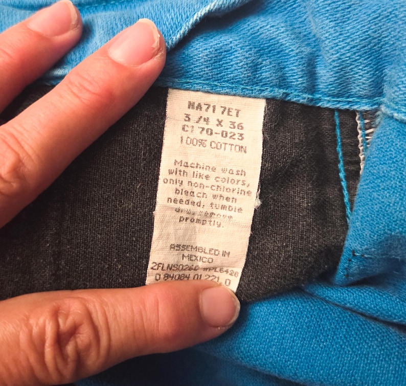 May include: Close-up of a tag from a pair of blue jeans. The tag reads "NA71 7ET 3/4 X 36 C170-023 100% COTTON". The tag also includes washing instructions and states "ASSEMBLED IN MEXICO".