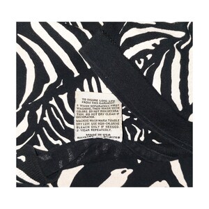 May include: Black and white zebra print garment with a tag that reads "TO INSURE LONG LIFE FROM THIS GARMENT". The tag also includes washing instructions and "MADE IN USA".