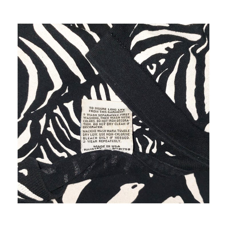 May include: Black and white zebra print garment with a tag that reads "TO INSURE LONG LIFE FROM THIS GARMENT". The tag also includes washing instructions and "MADE IN USA".