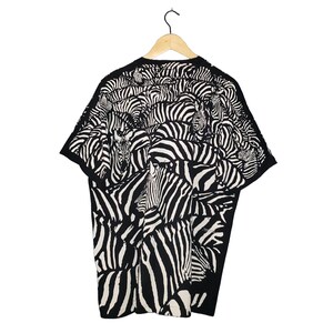 May include: Black and white zebra print t-shirt. The short-sleeved shirt features a repeating pattern of zebra stripes, creating a bold and eye-catching design. The shirt is hanging on a wooden hanger against a white background.