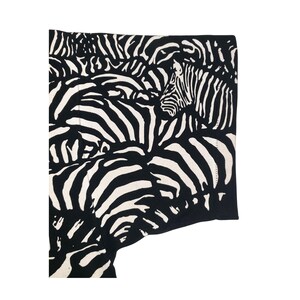 May include: Black and white zebra print fabric. The fabric features a repeating pattern of zebra stripes in black and white. The design is a close-up view of the zebra pattern, with the stripes creating a textured effect.