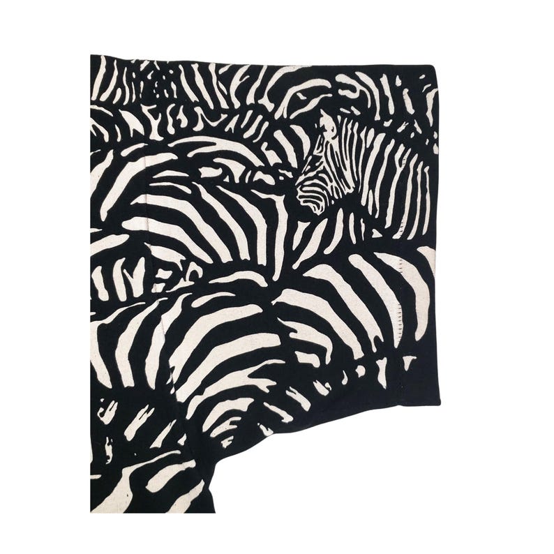 May include: Black and white zebra print fabric. The fabric features a repeating pattern of zebra stripes in black and white. The design is a close-up view of the zebra pattern, with the stripes creating a textured effect.