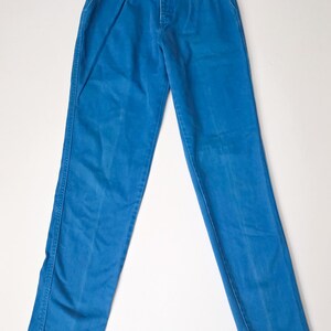May include: Bright blue high-waisted pants with a button-fly closure and decorative metal buttons. The pants have a classic straight-leg cut and feature front pleats. A vintage style garment.