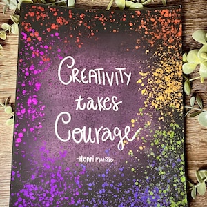 May include: A black canvas with a rainbow splatter paint background. The quote "Creativity takes courage - Henri Matisse" is written in white on the canvas.