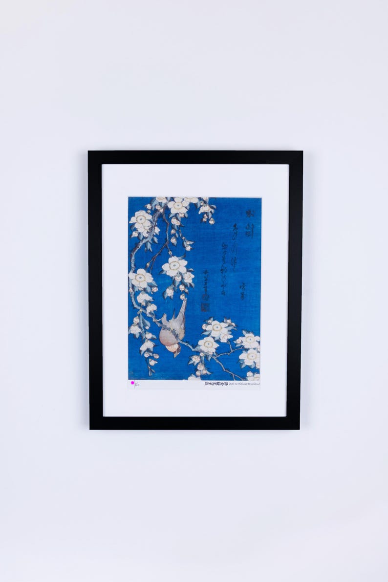 May include: Framed art print featuring a Japanese-style illustration. The artwork depicts a bird perched on a flowering branch against a blue background. The print is enclosed in a black frame, ready for display. The image includes Japanese characters.