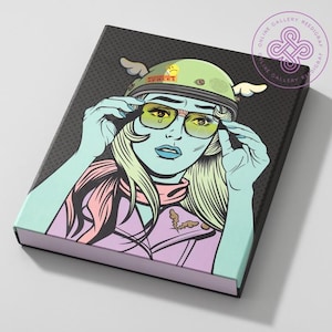 May include: A pop art style notebook featuring a woman wearing a green helmet with wings and yellow glasses. The woman has blue skin, blonde hair, and is wearing a pink scarf and jacket. The background is black with white dots.