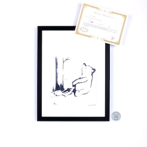 May include: A framed black and white ink illustration of a bear sitting under a tree, accompanied by a gold-bordered certificate of authenticity and a small circular sticker with a QR code. The artwork features a minimalist style with clean lines.