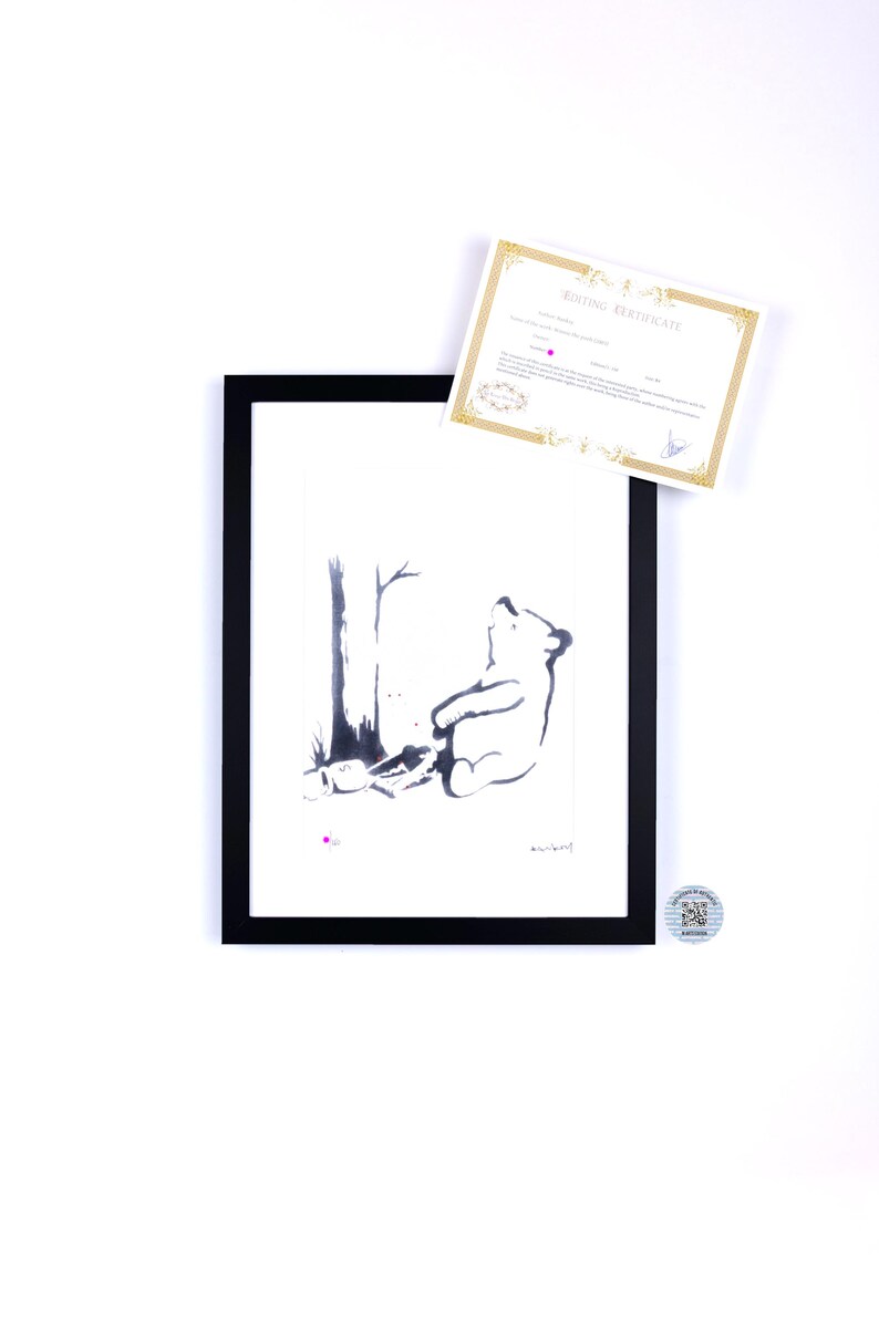 May include: A framed black and white ink illustration of a bear sitting under a tree, accompanied by a gold-bordered certificate of authenticity and a small circular sticker with a QR code. The artwork features a minimalist style with clean lines.