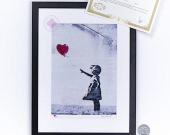 May include: A framed print featuring a black and white silhouette of a person reaching for a red heart-shaped balloon, accompanied by an editing certificate with gold border details and a small circular authentication sticker with a QR code.