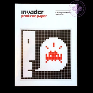 May include: A black and white cover of a book titled "Invader Prints on Paper" with a red pixelated alien on the front.