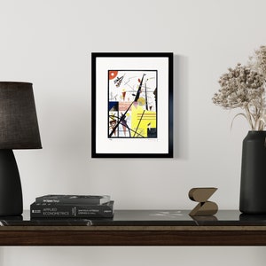 May include: A framed abstract art print with geometric shapes and lines in black, red, yellow, and white. The print is in a black frame and is hanging on a white wall.