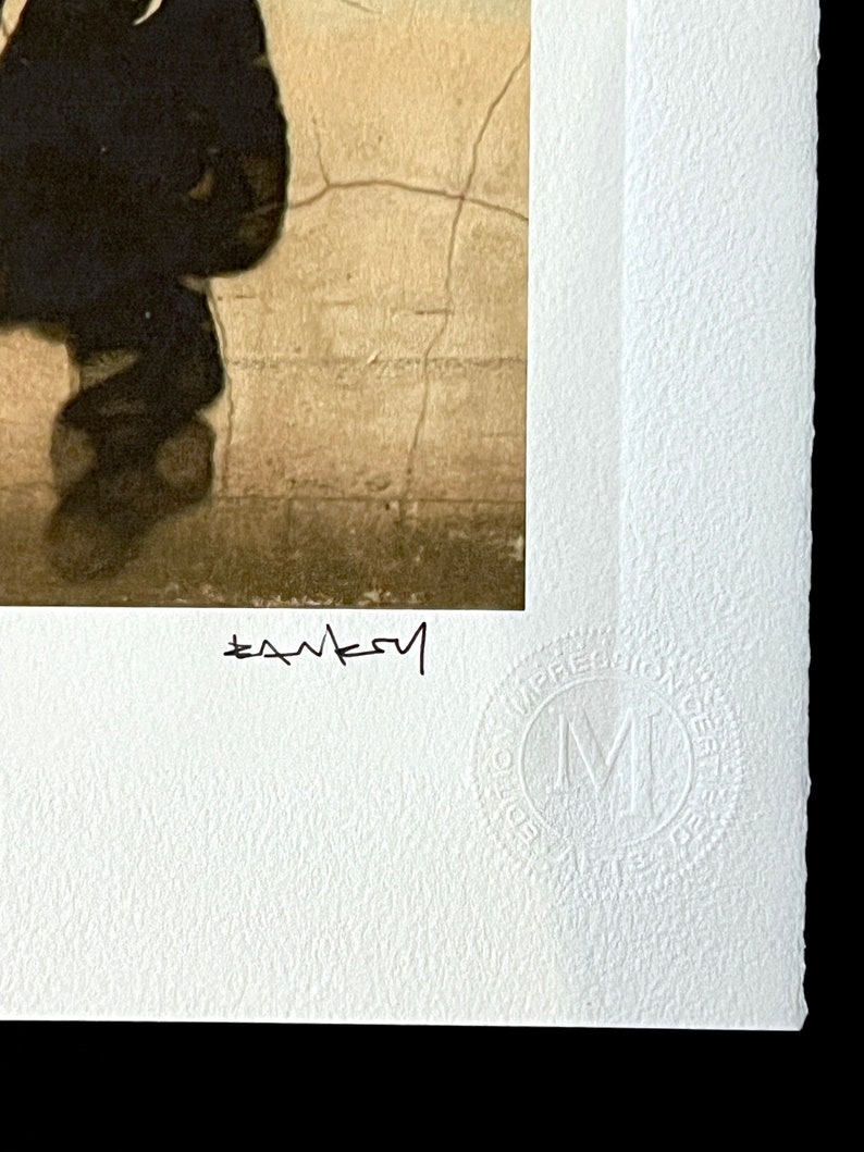 May include: A black and white photograph of a person walking away from the camera. The person is wearing a dark jacket and pants. The background is a cracked wall. The image is signed "Banksy" in the bottom left corner and has a "Made in the UK" stamp in the bottom right corner.
