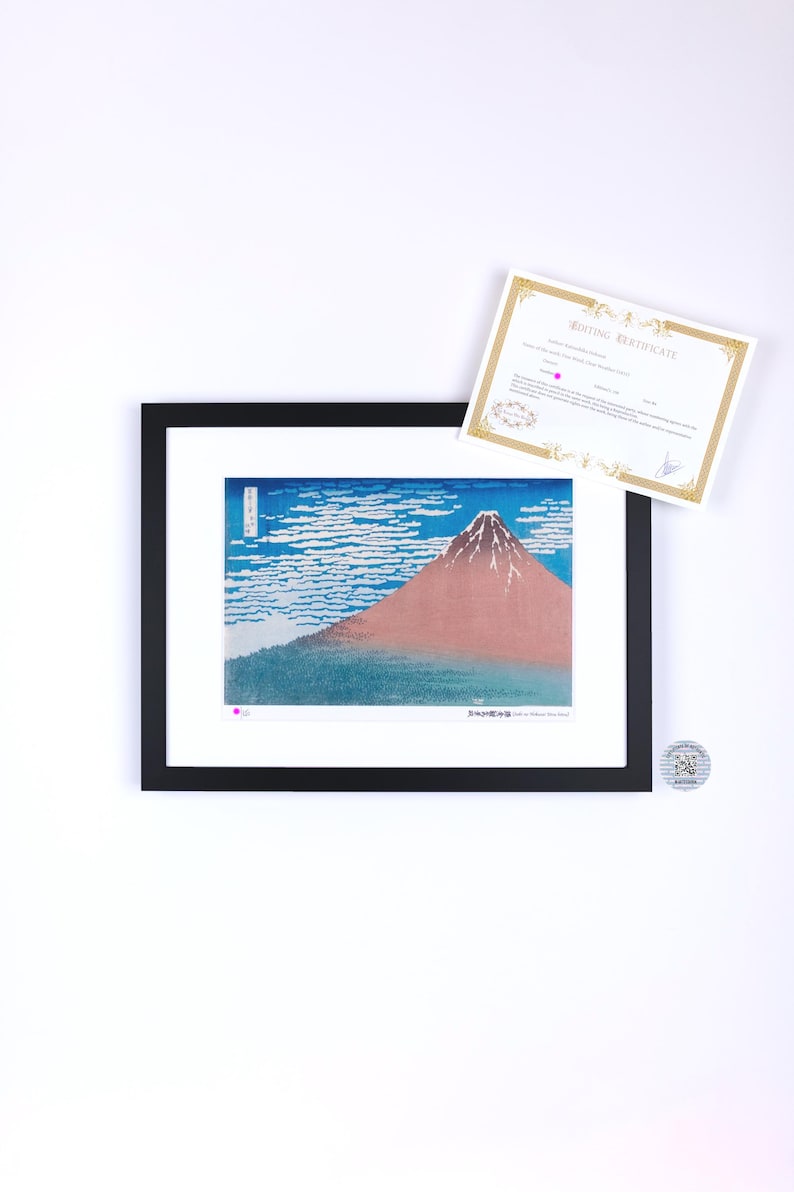 May include: Framed print of a Japanese landscape featuring Mount Fuji with a red peak, blue sky, and white clouds. The print is in a black frame with a white mat. A certificate is included.