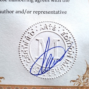 Puede incluir: Un certificado de papel blanco con un sello circular en relieve con el texto CERTIFIED ARTS EDITION IMPRES. Una letra M may&uacute;scula grande est&aacute; centrada en el sello y una firma en tinta azul est&aacute; escrita sobre la parte inferior del c&iacute;rculo.
