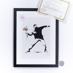 Peut inclure: Une impression encadrée en noir et blanc représentant une silhouette lançant un bouquet de fleurs colorées, avec un point rose et une signature en bas. Inclut un certificat d'authenticité à bordure dorée et un autocollant d'authentification.