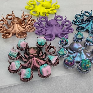 Puede incluir: Ocho figuritas de pulpo de colores con dados en sus tentáculos. Las figuritas de pulpo están hechas de resina y están pintadas en varios colores, incluyendo morado, azul, verde y marrón. Los dados también son coloridos y tienen diferentes números.
