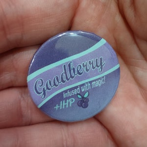 May include: A purple and teal button with the text "Goodberry" and "Infused with magic!"  The button also has a small image of a blueberry.