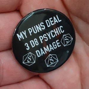 May include: Black button with white text that reads "My puns deal 3 d8 psychic damage" and three white dice with the number 8 on them.