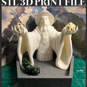 May include: White 3D printed figurine of a wizard holding dice. The wizard is wearing a robe and has a long white beard. The dice are green and yellow and are in a tray in front of the wizard. The tray is also 3D printed and has a hexagonal shape.