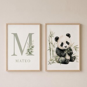May include: Two framed wall art prints with light wood frames. The left print features a large sage green letter M with botanical leaves and the name MATEO below. The right print shows a watercolour illustration of a panda sitting among bamboo stalks.