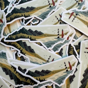 May include: A collection of stickers featuring a landscape design. The stickers depict a coastal scene with mountains, a lighthouse, and the outline of a state. The color palette includes greens, blues, and browns.