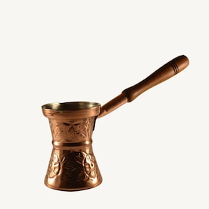 Peut inclure: Une cafetière en cuivre avec une poignée en bois et des motifs floraux complexes. La cafetière est en cuivre poli et présente un design turc traditionnel.