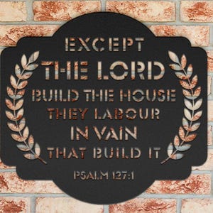 May include: Black metal wall art with the text "EXCEPT THE LORD BUILD THE HOUSE THEY LABOUR IN VAIN THAT BUILD IT" and "PSALM 127:1". The sign has a decorative border and is mounted on a brick wall.