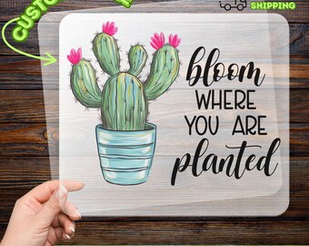 May include: A DTF transfer featuring a cactus in a blue pot with pink flowers. The text "bloom where you are planted" is displayed in black script. The transfer is customizable and ready to apply.