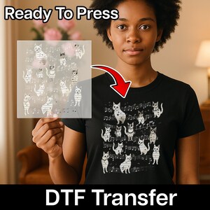 May include: A black t-shirt featuring a white graphic print of multiple cats interspersed with musical notes and staff lines. A transparent sheet displaying the same cat and musical note design is held up, showing the Ready To Press DTF Transfer.