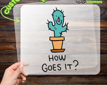 May include: A DTF transfer featuring a cartoon cactus in a pot with the text "HOW GOES IT?". The cactus is light blue with black spines and a pink mouth. The transfer is on a clear sheet with the words "CUSTOMIZABLE" and "READY TO APPLY" in green.