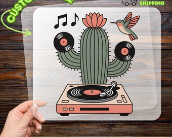 May include: A DTF transfer featuring a cactus with vinyl records as arms, a hummingbird, and musical notes. The cactus sits atop a record player. The words "CUSTOMIZABLE" and "READY TO APPLY" are also visible.