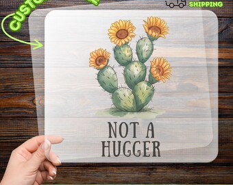 May include: A DTF transfer featuring a cactus with yellow and orange flowers. The text "NOT A HUGGER" is below the cactus. The word "CUSTOMIZABLE" is at the top left, and "READY TO APPLY" is at the top right.