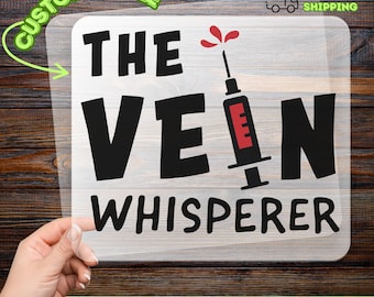 May include: A clear DTF transfer sheet featuring the black text THE VEIN WHISPERER with a graphic of a syringe replacing the letter I. The syringe has a red barrel and a small red splash above it. The design is printed on a transparent film.
