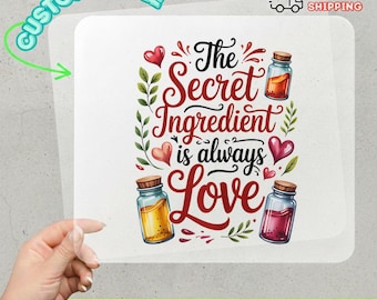 May include: A DTF transfer with the text "The Secret Ingredient is always Love." The design includes decorative jars, hearts, and leaves. The words "Customizable" and "Ready to Apply" are also visible.