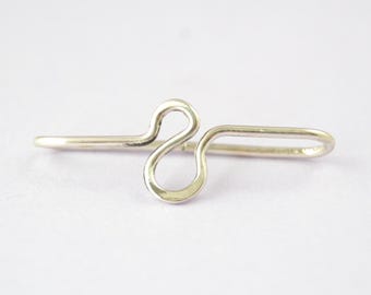 May include: A silver-colored ring with a unique, abstract design. The ring features a looping, figure-eight-like shape in the center, with a straight band extending on either side. The ring is set against a plain white background.
