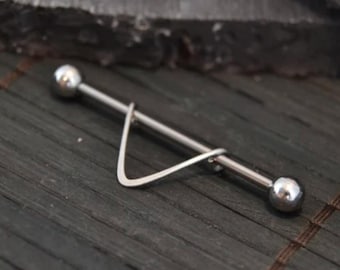 May include: A silver barbell with a triangular shaped charm. The barbell is designed for body piercing.