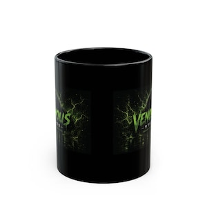 Peut inclure: Un mug en céramique noire arborant un motif graphique avec un effet d'éclaboussure liquide vert et le texte "VENOMOUS STUDIOS" imprimé dans une police dentelée et stylisée. Le motif est placé sur un fond sombre sur le côté du mug.