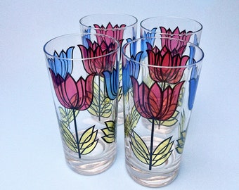 May include: Set of four clear glass drinking glasses with a colorful tulip design. The tulips are outlined in black and filled with shades of pink, blue, and yellow.